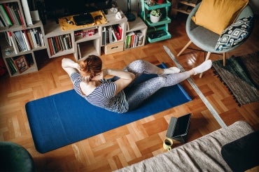woman doing crunches on a yoga mat in her living room