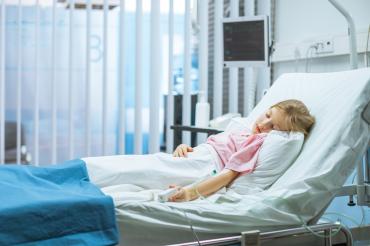 A young girl sleeps in a hospital bed