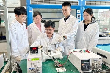 Huazhong University of Science and Technology researchers gather around an electrolyzer 