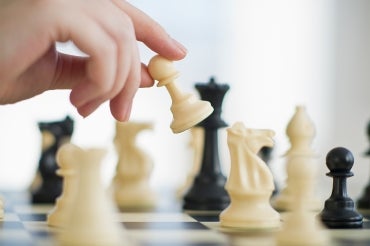 hand moving a chess piece on a chessboard