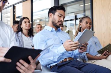 Working professionals in a workshop setting, holding tablets