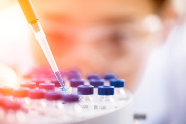 female scientist using a dropper in a tray of tube