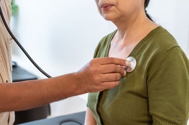 a doctor examines the heart of a south asian woman with a stethoscope