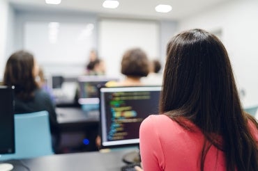 a woman sits in a computer science classroom