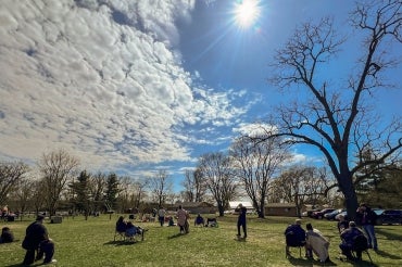 several people sit in a park to view the 2024 total eclipse in Chiefswood Park
