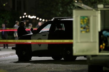 a police officer stands guard behind police tape at a police involved shooting