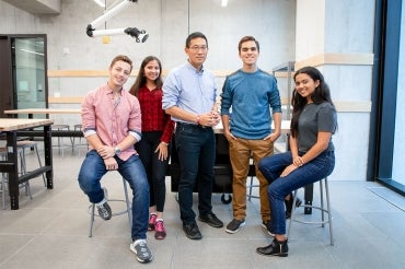 Chris Yip poses in an engineering lab with four Pearson Scholars 
