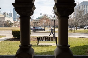 a view of convocation hall across front campus from behind a pair of close up pillars