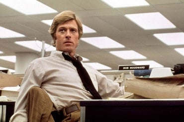 Robert Redford as Bob Woodward sits at a desk in a still from the movie All the President's Men