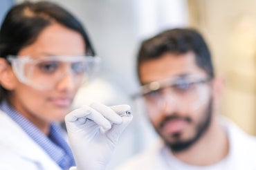 Pranav Kadhiresan and Buddhisha Udugama hold up the pea-sized heating device