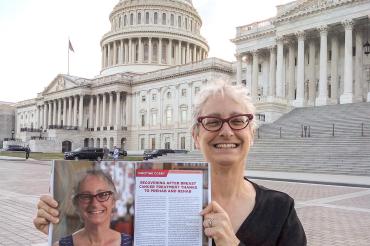 Christine Crosby in Washington, DC standing in front of the capitol buildings holding up a magazine with a story about her