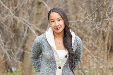 Cylita Guy stands in a field wearing a sweater