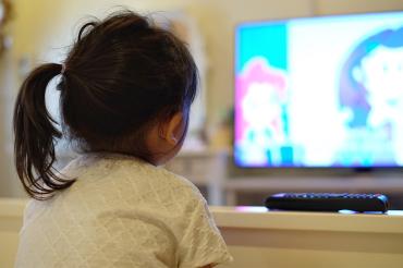 a young asian girl watches tv