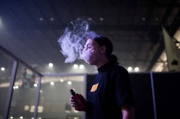 a young person is seen vaping in a dark room