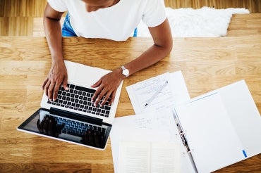 A woman works on a laptop at a table at home