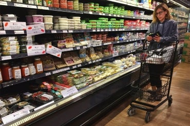 a woman checks her phone while shopping in a grocery store in Toronto