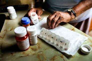 a senior citizen refills a medication dispenser with various medications