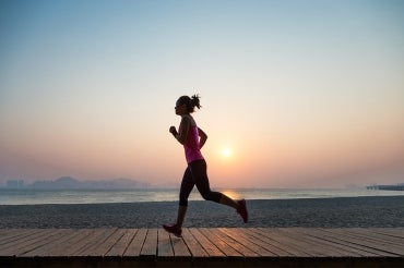 a young woman jogs along the boardwalk at sunrise