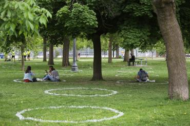 Park goers sit in circles painted on the grass in Toronto's Trinity Bellwoods Park