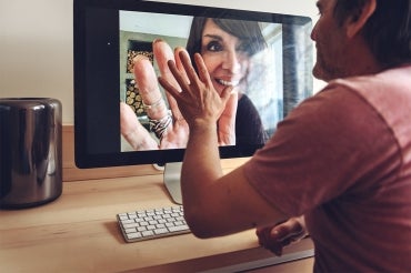 man speaks to woman and virtually press their hands together over video chat