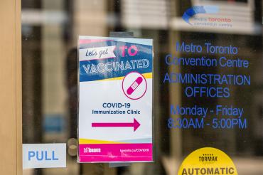 a sign directing people to the metro toronto convention centre vaccine clinic entrance