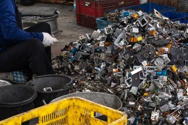 a person sorts through a pile of electronic waste in Thailand