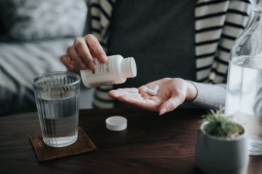 woman taking pill from bottle