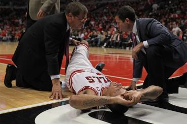 an injured derrick rose is attended to by medics on the basketball court