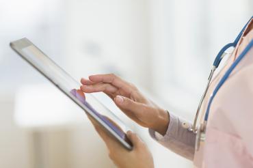 an anonymous female nurse holds an ipad