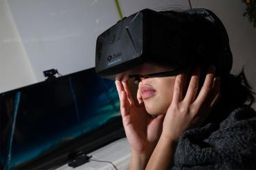 a southeast asian woman wears an oculus headset in a darkened room