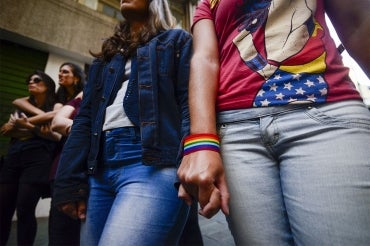 a row of 4 women hold hands as they march in a LBGT parage in Sao Paulo Brazil