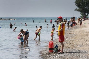 A lifeguard stands watch over swimmers at a Toronto beach