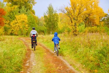 Father takes his two children cycling through a forest trail