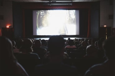 Stock photo of the backs of heads in a movie theatre
