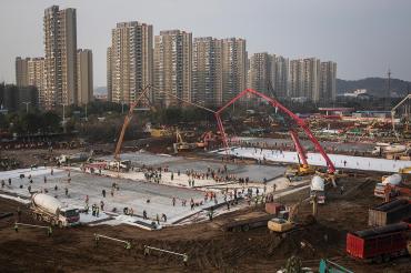 Photo of cranes and construction workers at the site of two new hospitals in Wuhan, China
