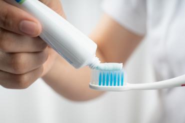 Photo of toothpaste being applied to toothbrush.