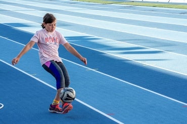 Young girl practices with a soccer ball at the university of toronto