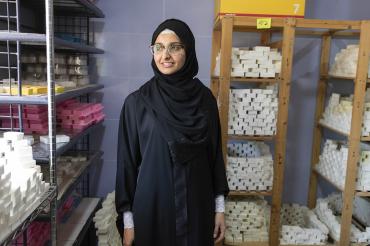 a Jordanian sitti soap employee stands in a storeroom surrounded by bars of soap