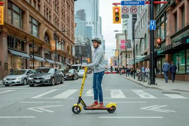 man rides a roll electric scooter in downtown toronto
