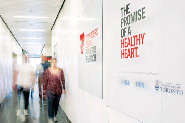 people walking down a corridor at the Ted Rogers Centre for Heart Research. On the wall it reads "The promist of a healthy heart"