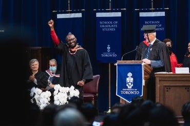 Black male graduate pumps fist in air on stage at Rotman convocation 