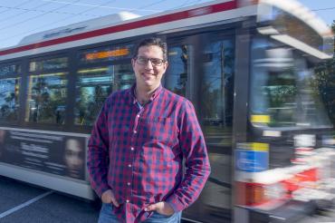 Steven Farber outside with a bus passing behind him