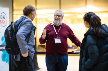 Michael Sefton speaks with two attendees at the Medicine By Design symposium at the Mars Discovery District