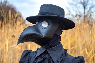 Madeleine Mant wears a plague doctor mask