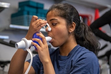 A student breathes into a machine that tests her respiratory levels 