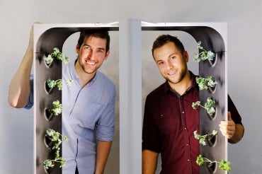 Conner Tidd and Kevin Jakiela are pictured looking through one of their hydroponic growing towers