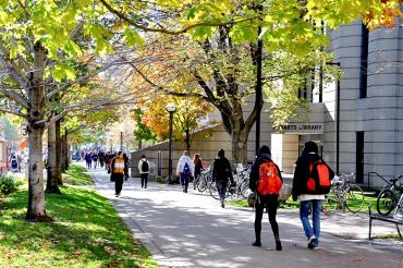 Students walking past robarts library from north to south surrounded by green foliage