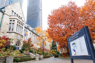 A photo of St. Michael's College sign with a building and tree in the background