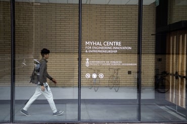A student walks behind a glass wall at U of T's Myhal Centre