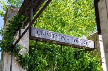 Gates that say University of Toronto with trees